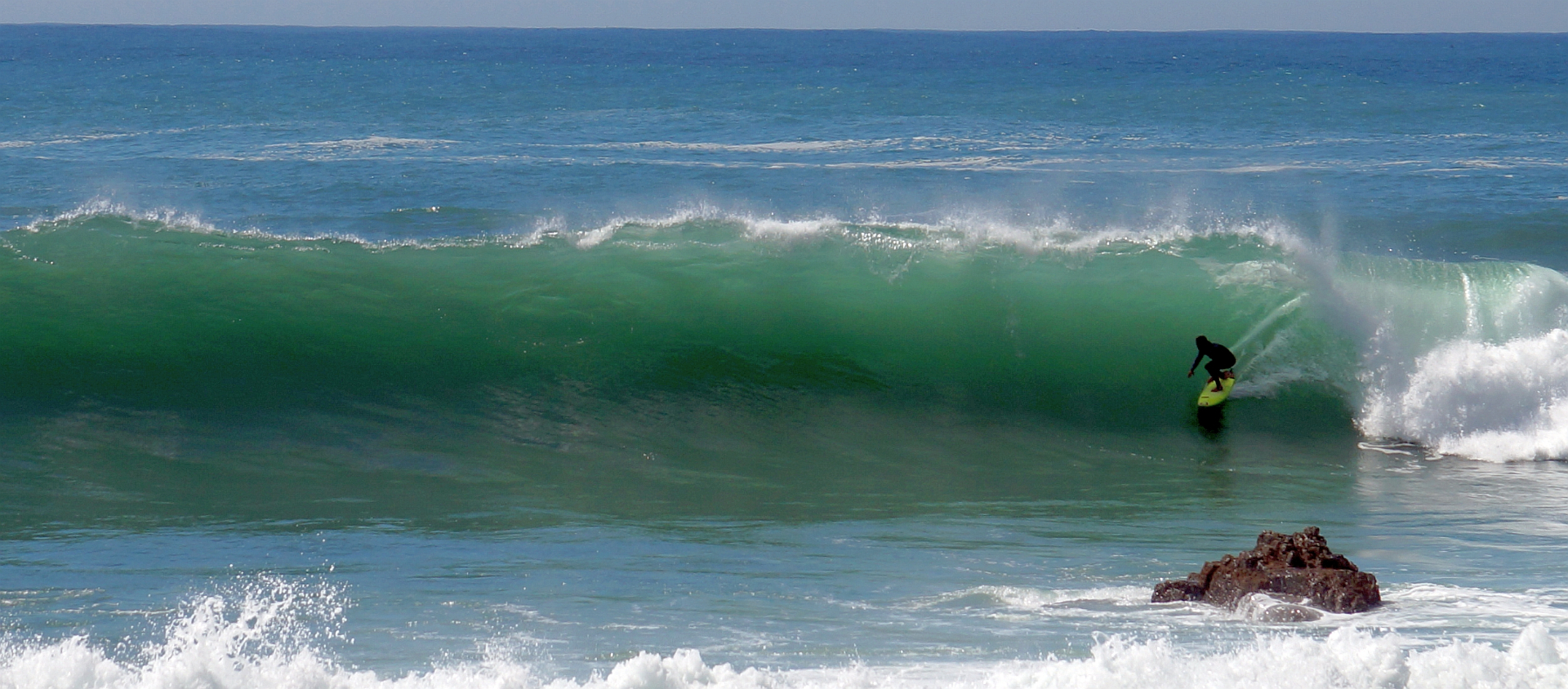 Surfer riding a clean wave on the west coast of Sagres during a guiding session