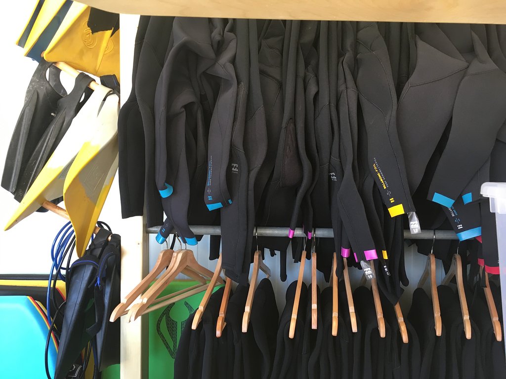 Rental wetsuits hanging on a rail at the FreeRide surf centre in Sagres