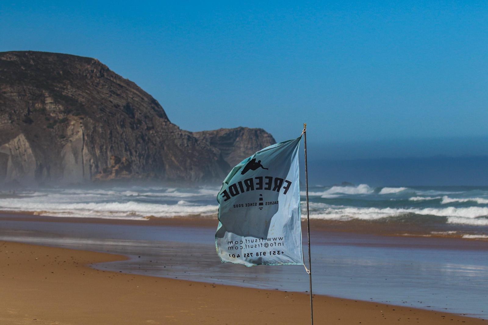 FreeRide flag on an empty west-coast beach near Sagres with Atlantic surf behind